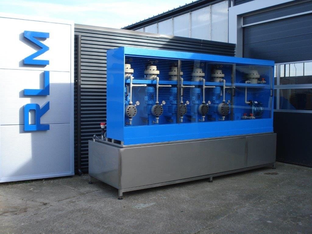 Blauwe doseerkast met vijf doseerpompen achter een open front, op een rvs lekbak buiten voor het pand