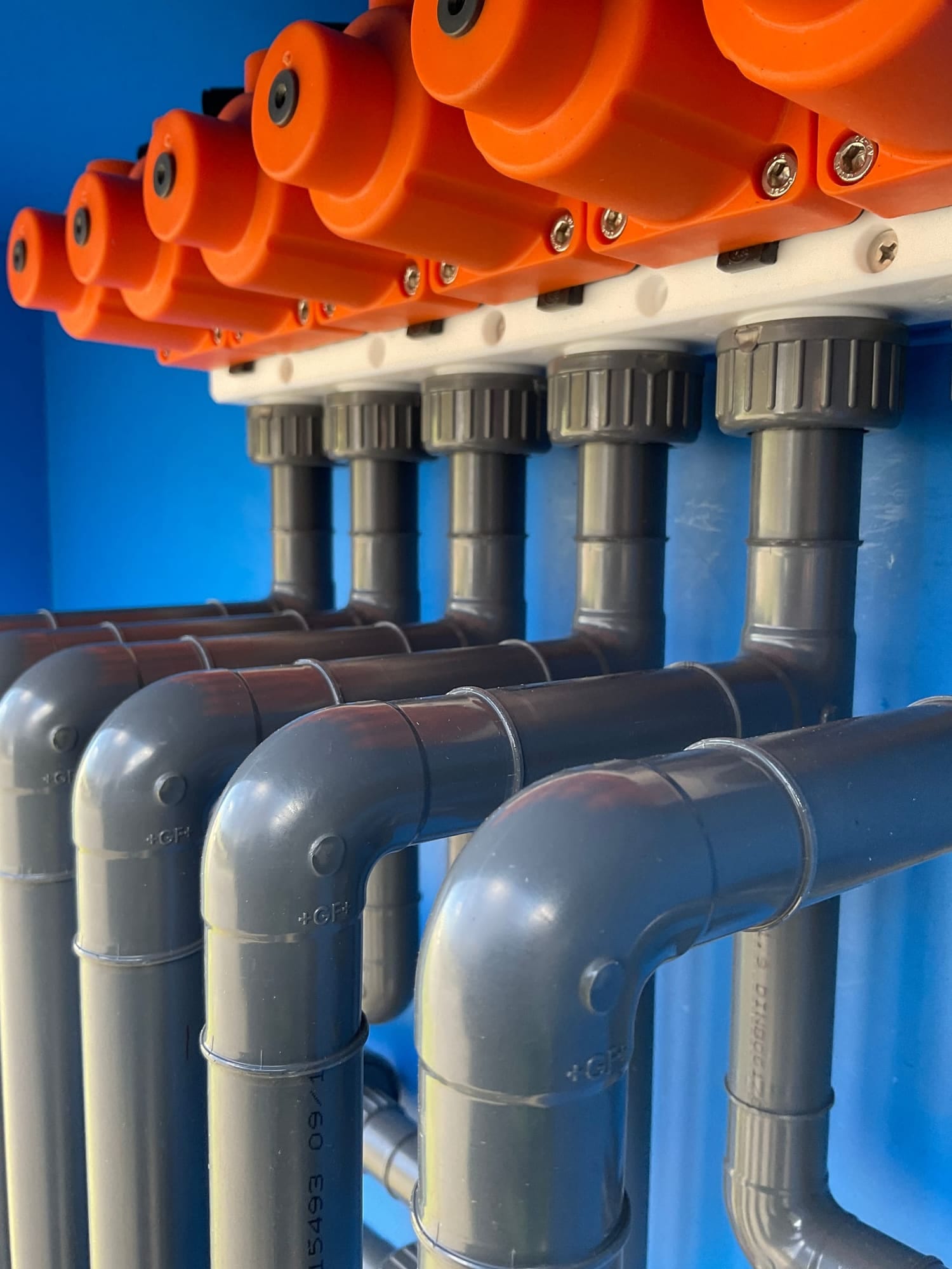 Doseerkast met grijs PVC-leidingwerk en oranje handafsluiters, gebouwd in de werkplaats van RLM