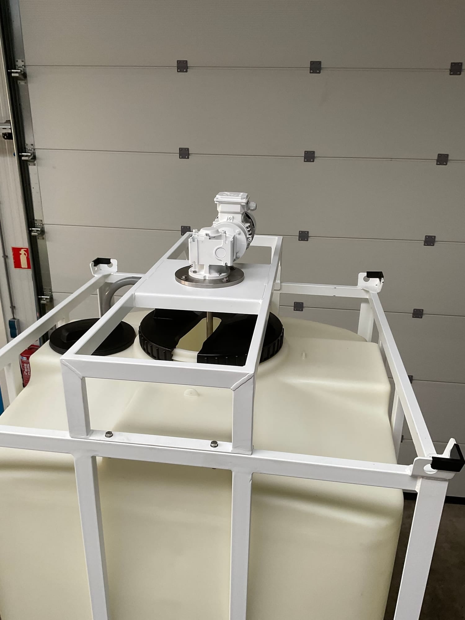Wit gelakt stalen frame om een vierkante PE-tank, met een roerwerk op de traverse boven het mangat