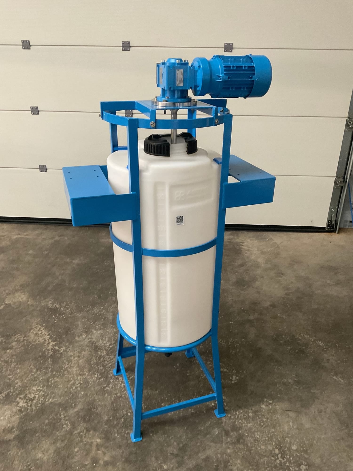 Witte conische doseertank in een blauw stalen frame, met een blauw roerwerk met reductor op het deksel