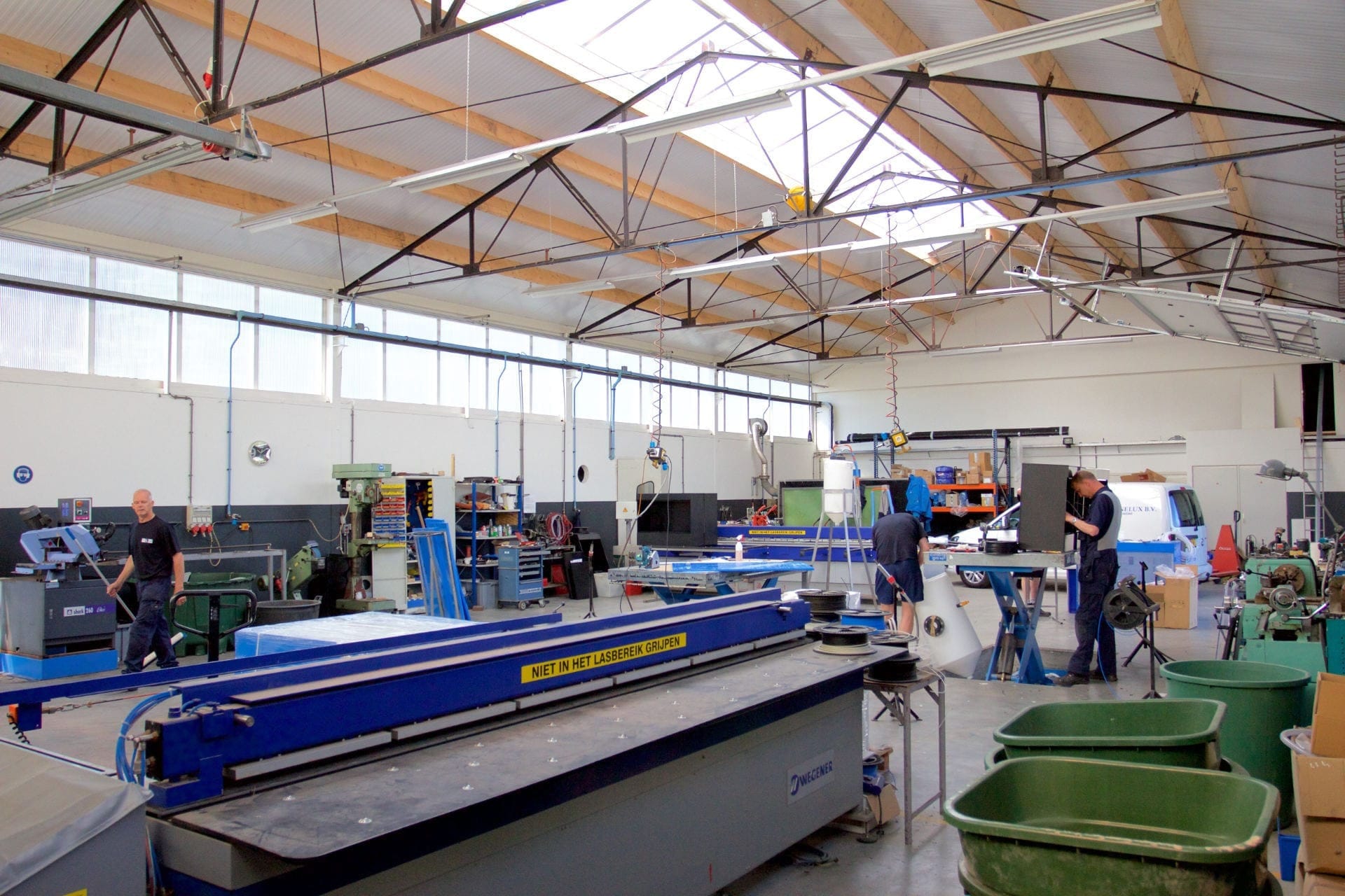 De werkplaats van RLM in Driezum met lasbank, CNC-machines en medewerkers aan het werk