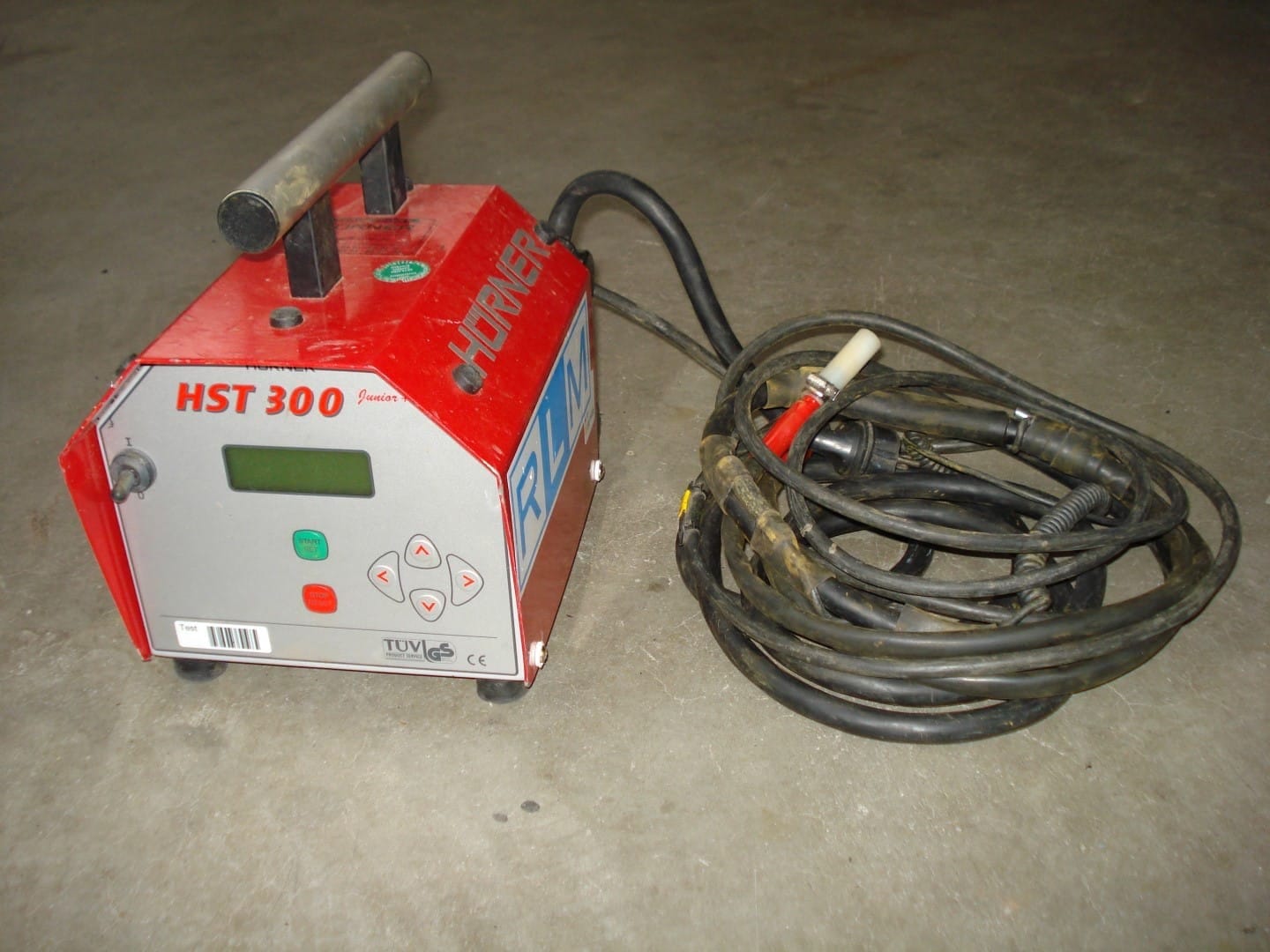 Rood HÜRNER HST 300 elektrolasapparaat met opgerolde laskabels en een RLM-sticker op de behuizing