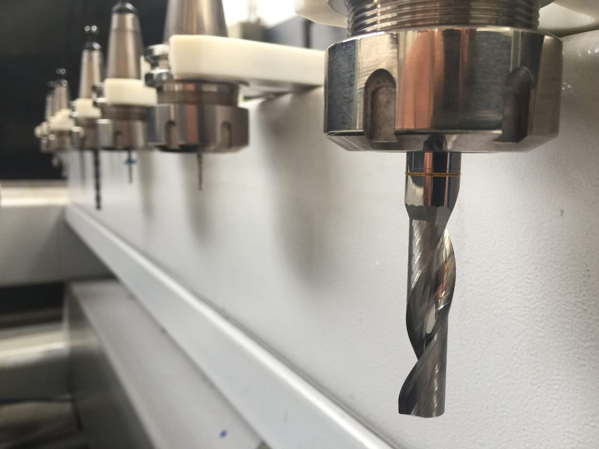 Frezen in de gereedschapswisselaar van de CNC-freesmachine, met een tweesnijder scherp op de voorgrond