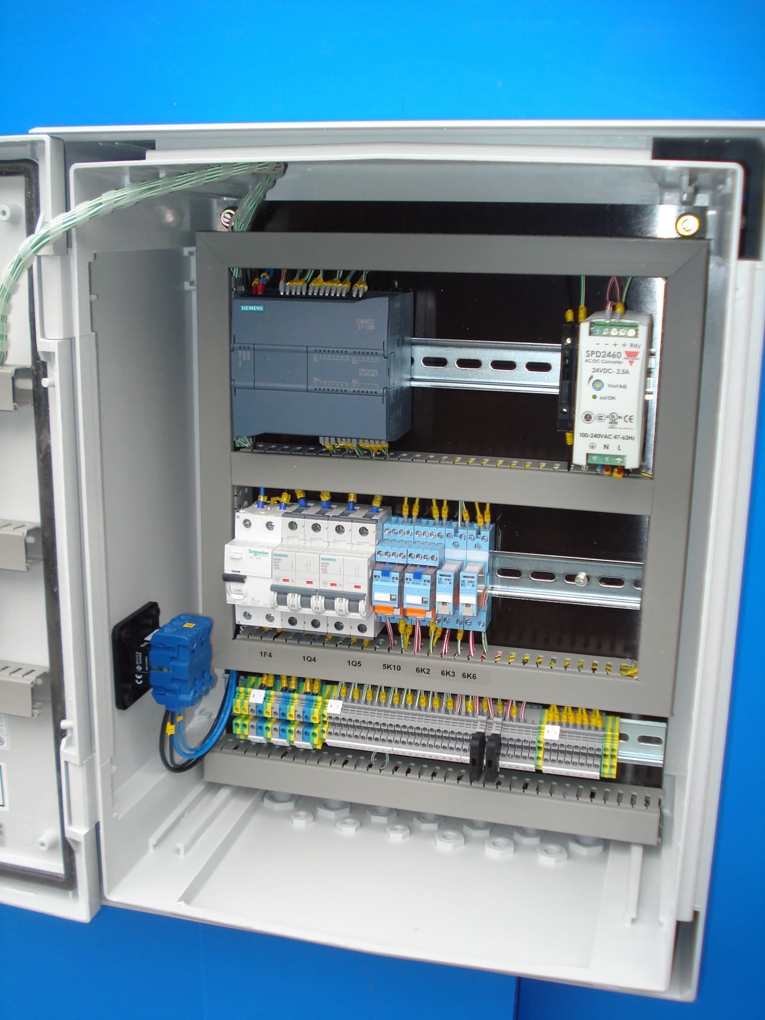 Binnenzijde van een besturingskast met Siemens-PLC, installatieautomaten, overspanningsbeveiliging en een klemmenstrook
